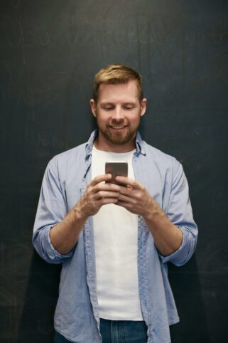 This is an image of a man in a blue shirt looking at their phone